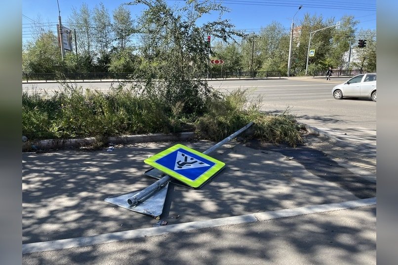 Знак пешеходного перехода лежит на тротуаре в Чите